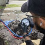 Plumber in Cape Coral, FL inspecting a handheld plumbing diagnostic device while evaluating a residential water system.