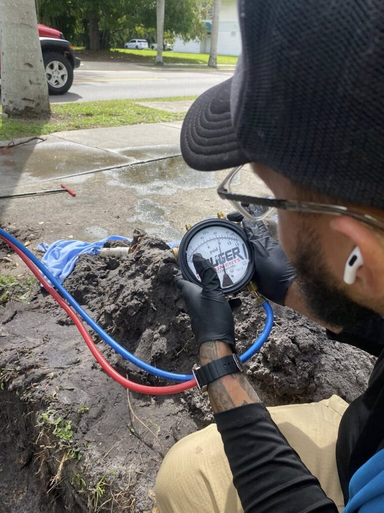 Plumber in Cape Coral, FL inspecting a handheld plumbing diagnostic device while evaluating a residential water system.